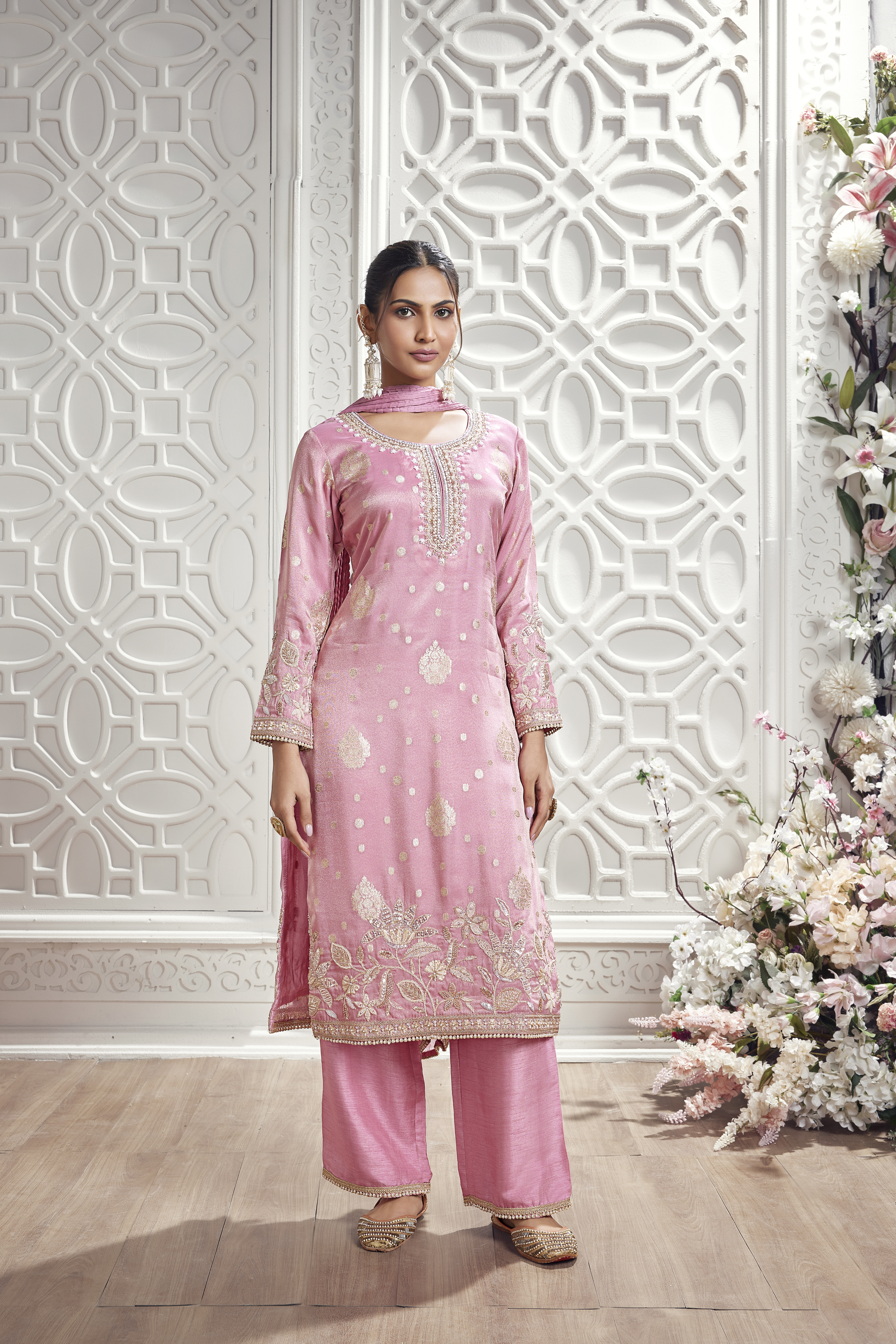 Woman wearing blush pink embroidered silk kurta set with palazzo pants and matching dupatta.