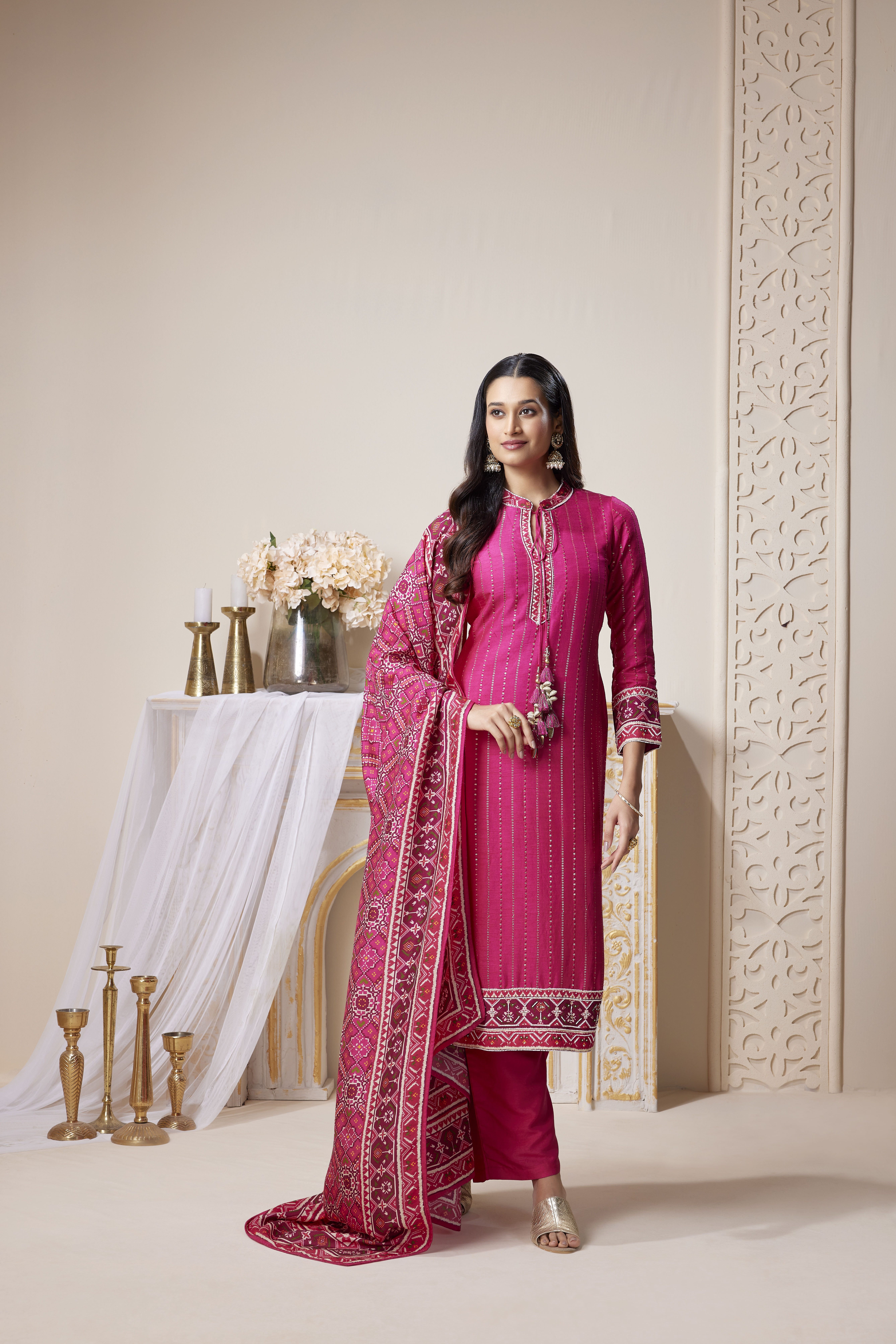 Woman wearing rani pink embroidered kurta set with ethnic dupatta and straight pants, festive traditional outfit