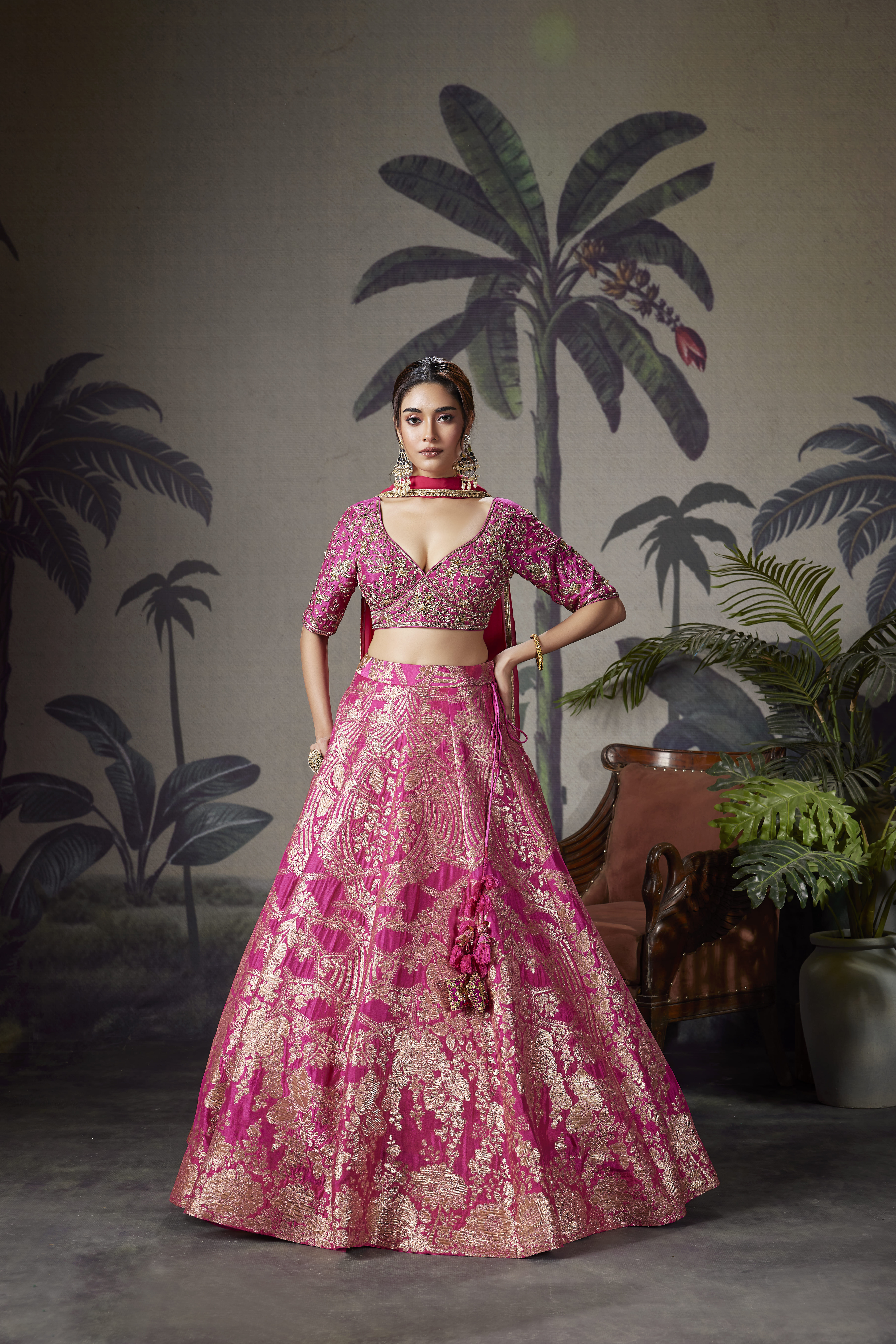 Woman wearing rani pink zari woven lehenga with embroidered blouse and dupatta, traditional bridal style outfit with heavy festive look