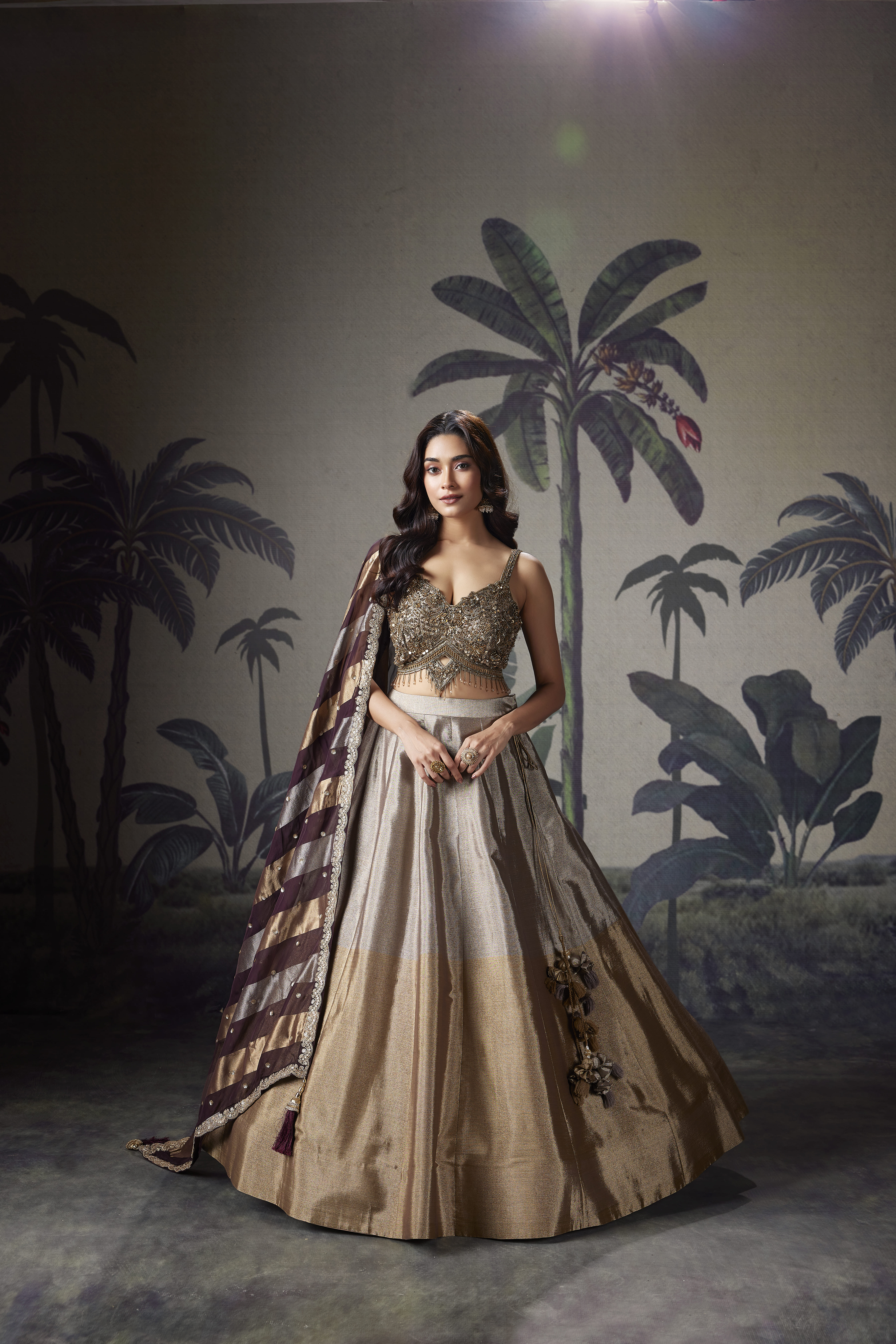 Woman wearing champagne gold lehenga with embellished blouse and striped dupatta, elegant bridal style outfit with luxurious festive look