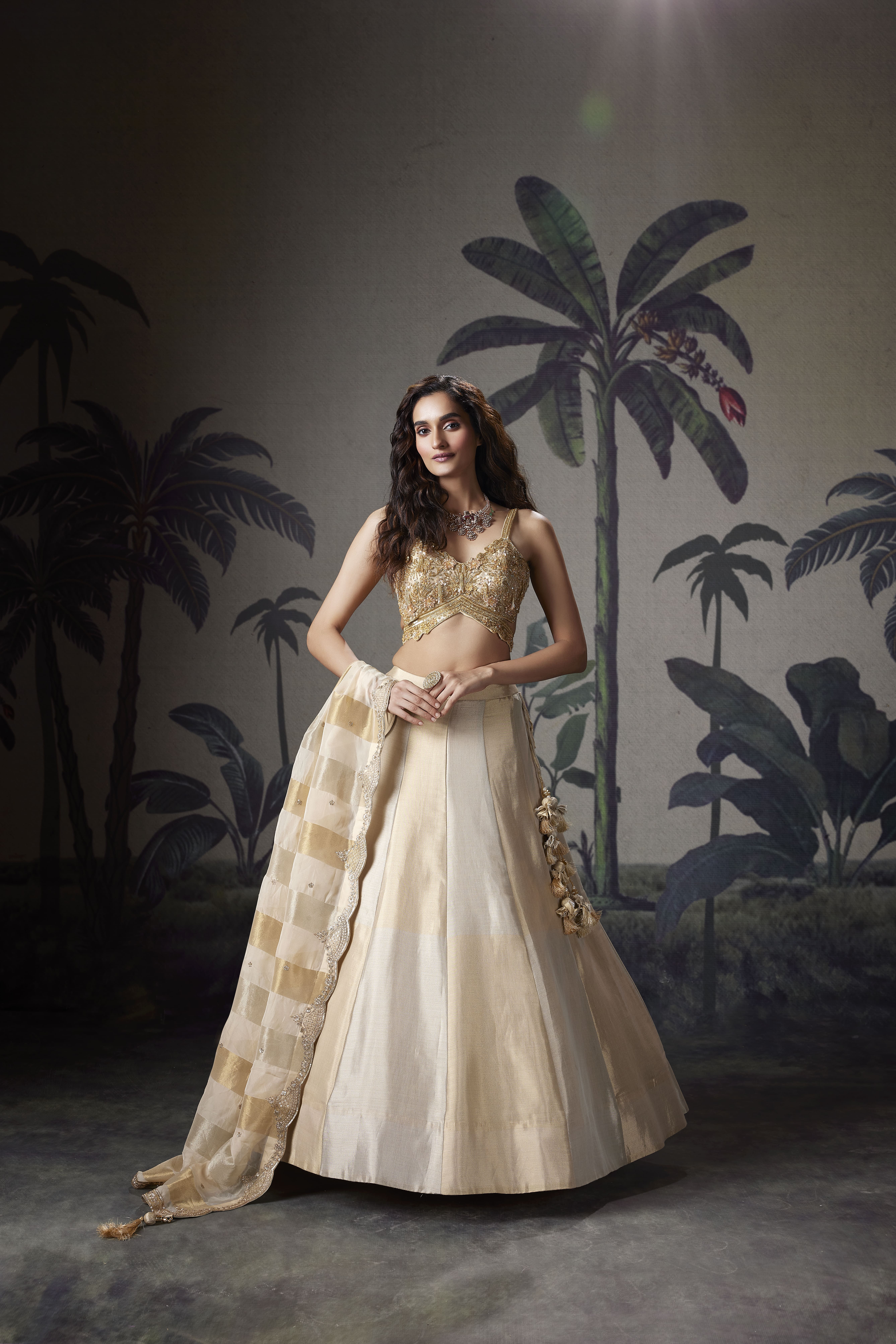 Woman wearing champagne gold lehenga with embroidered blouse and dupatta, elegant festive ethnic outfit with soft shimmer and modern styling