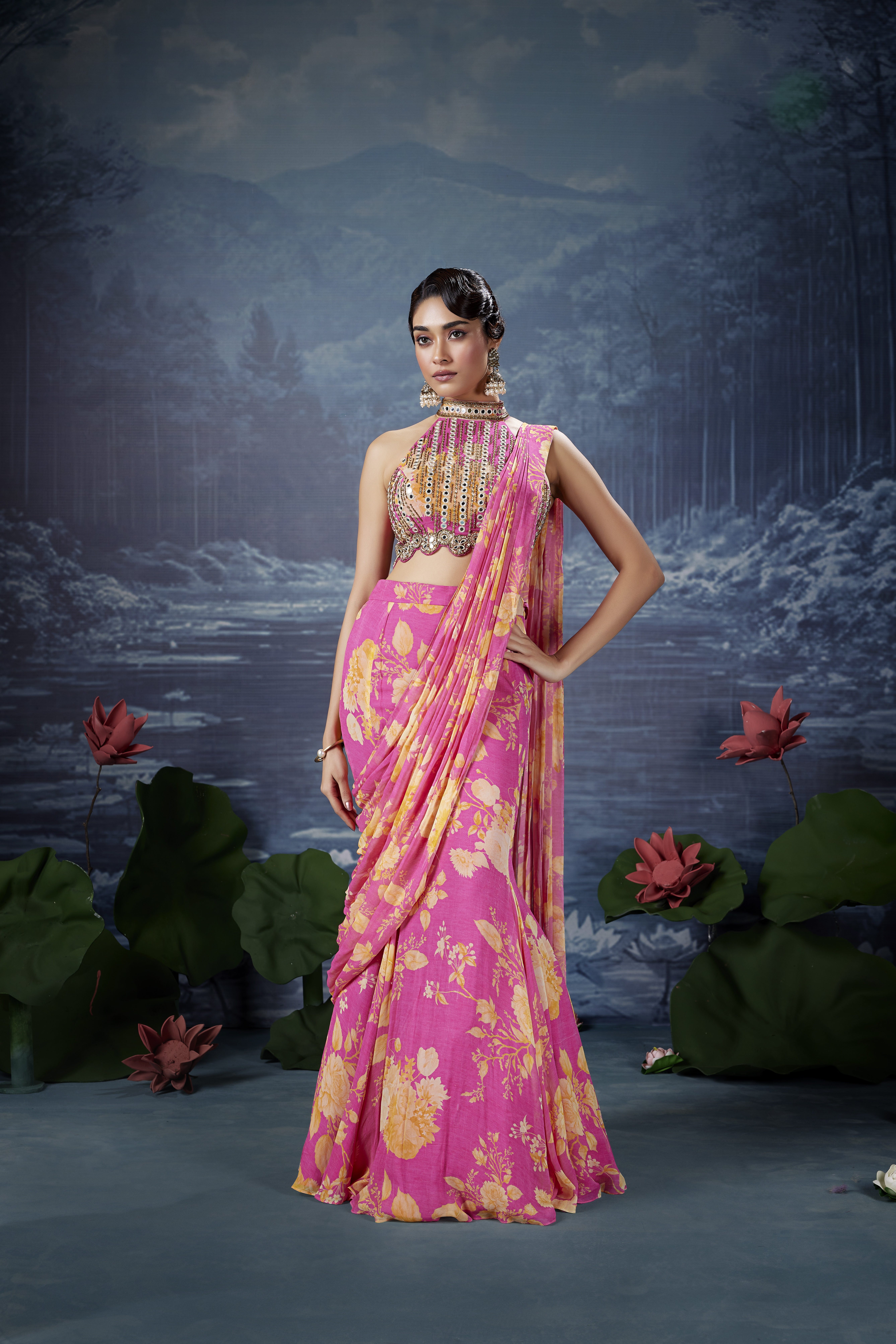 Woman wearing a rani pink floral saree with an embellished halter-neck blouse and intricate embroidery.