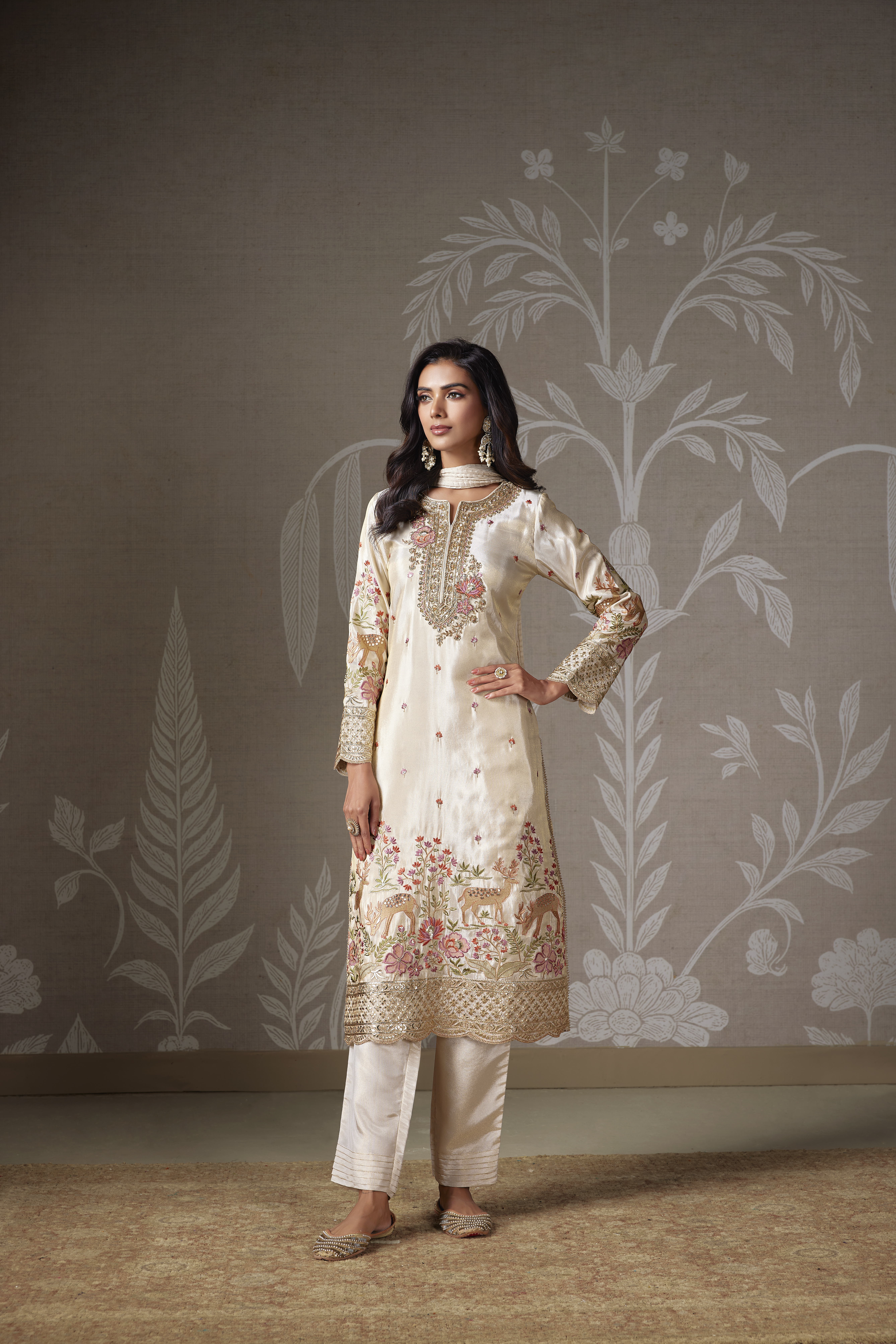 Woman wearing an ivory floral embroidered silk kurta set with straight pants and matching dupatta.