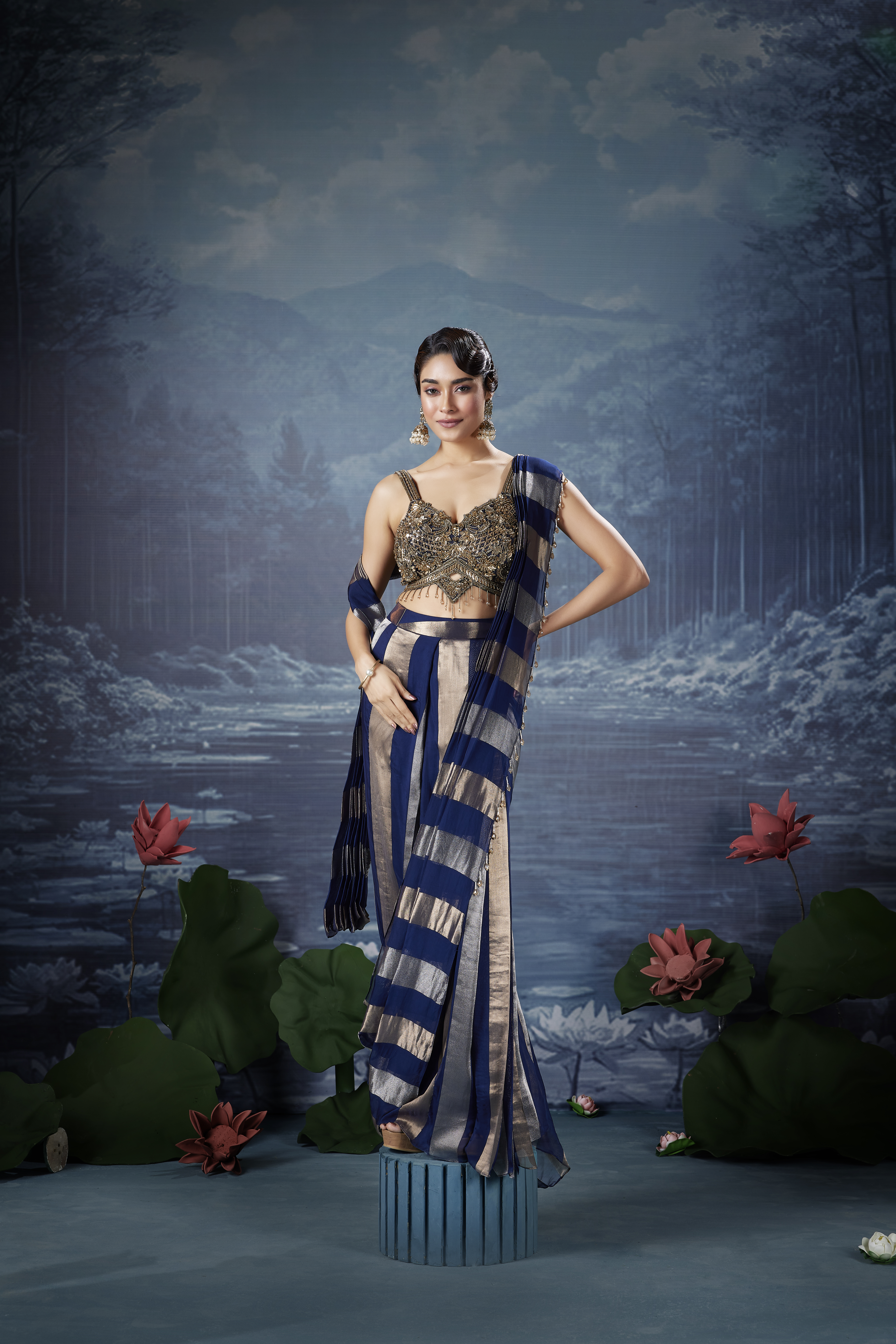 Woman wearing a navy blue metallic striped saree with a heavily embellished designer blouse.