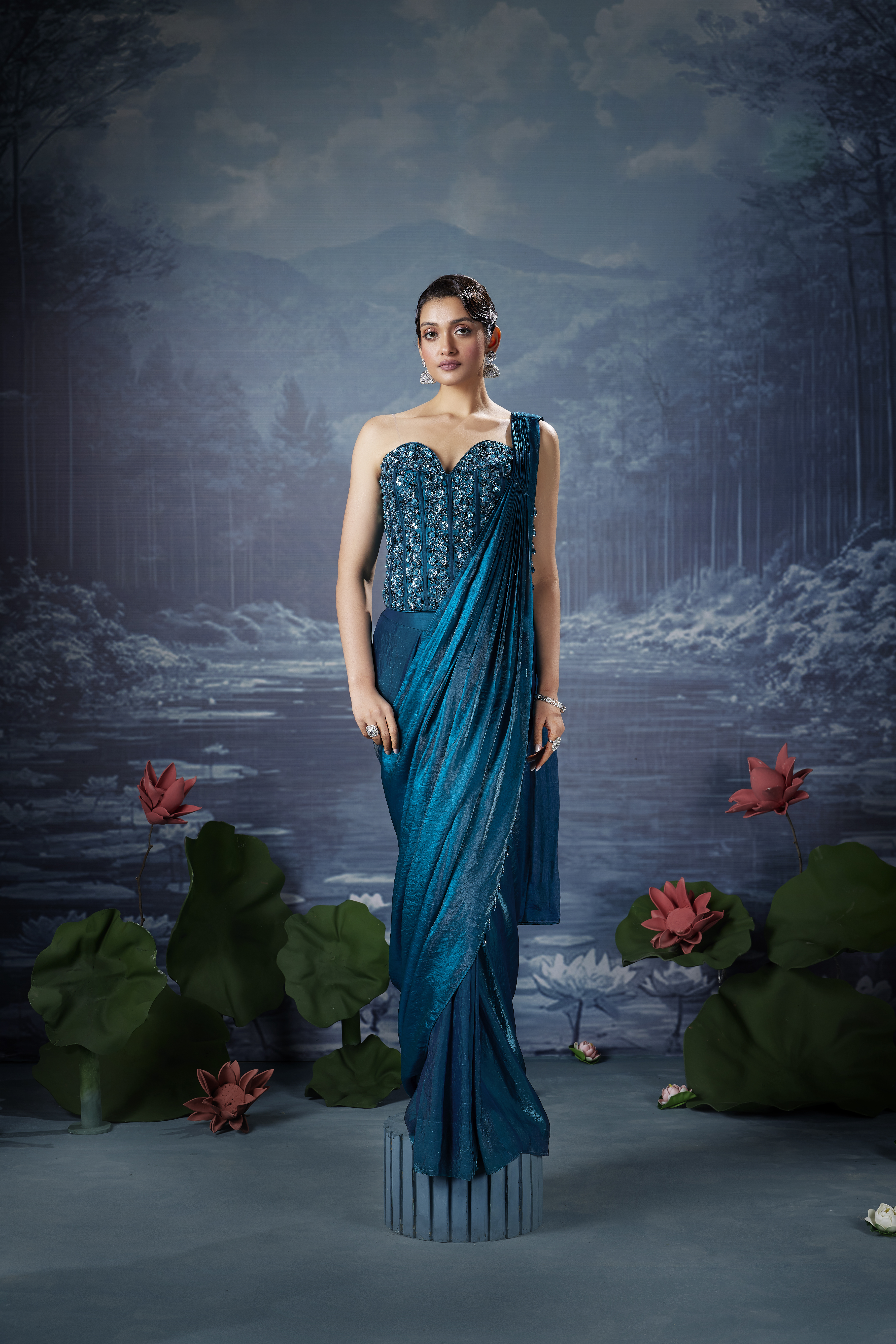 Woman wearing a midnight teal designer saree with an embellished corset blouse and sweetheart neckline.