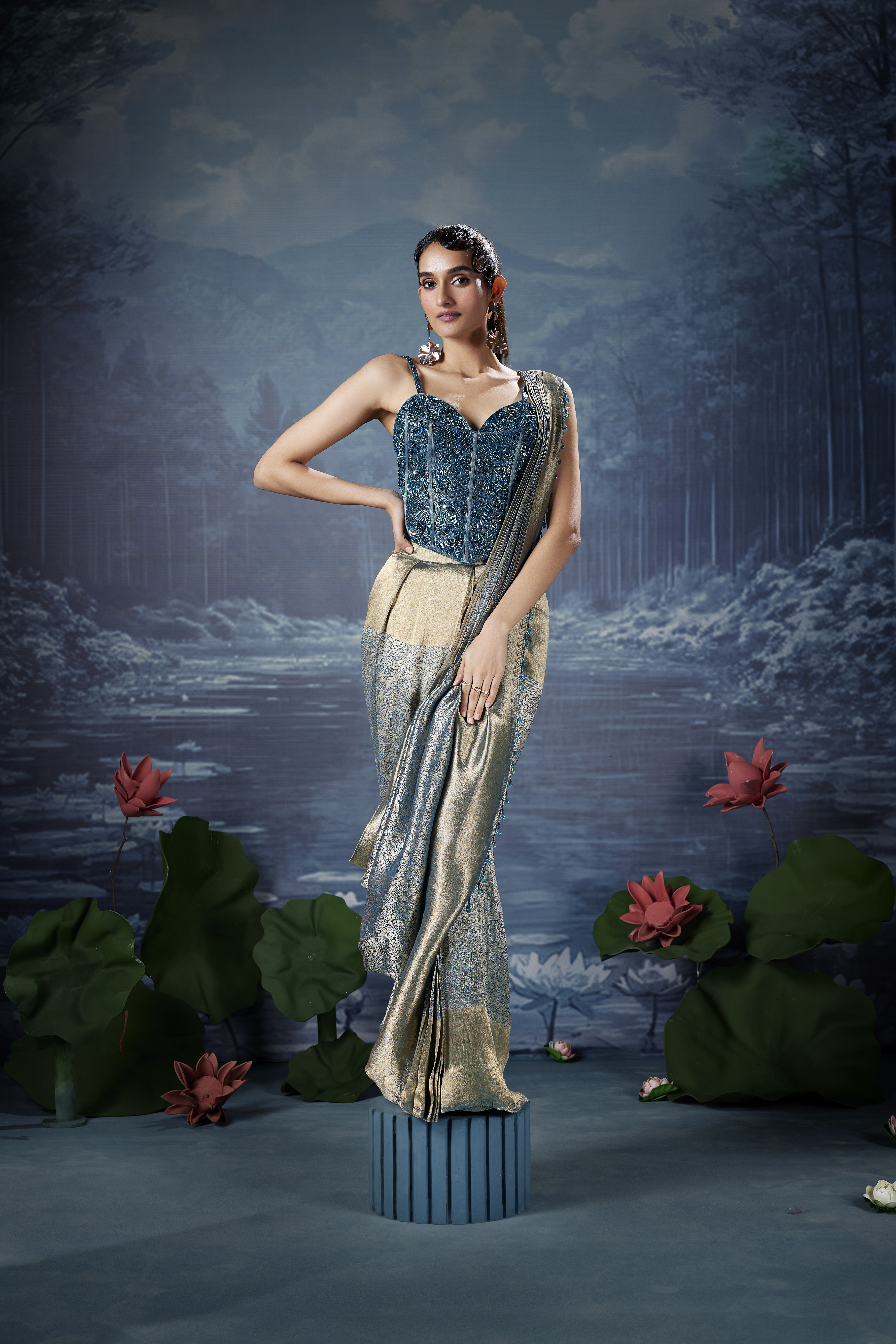 Woman wearing a champagne gold tissue saree with a teal embellished corset blouse and sweetheart neckline.