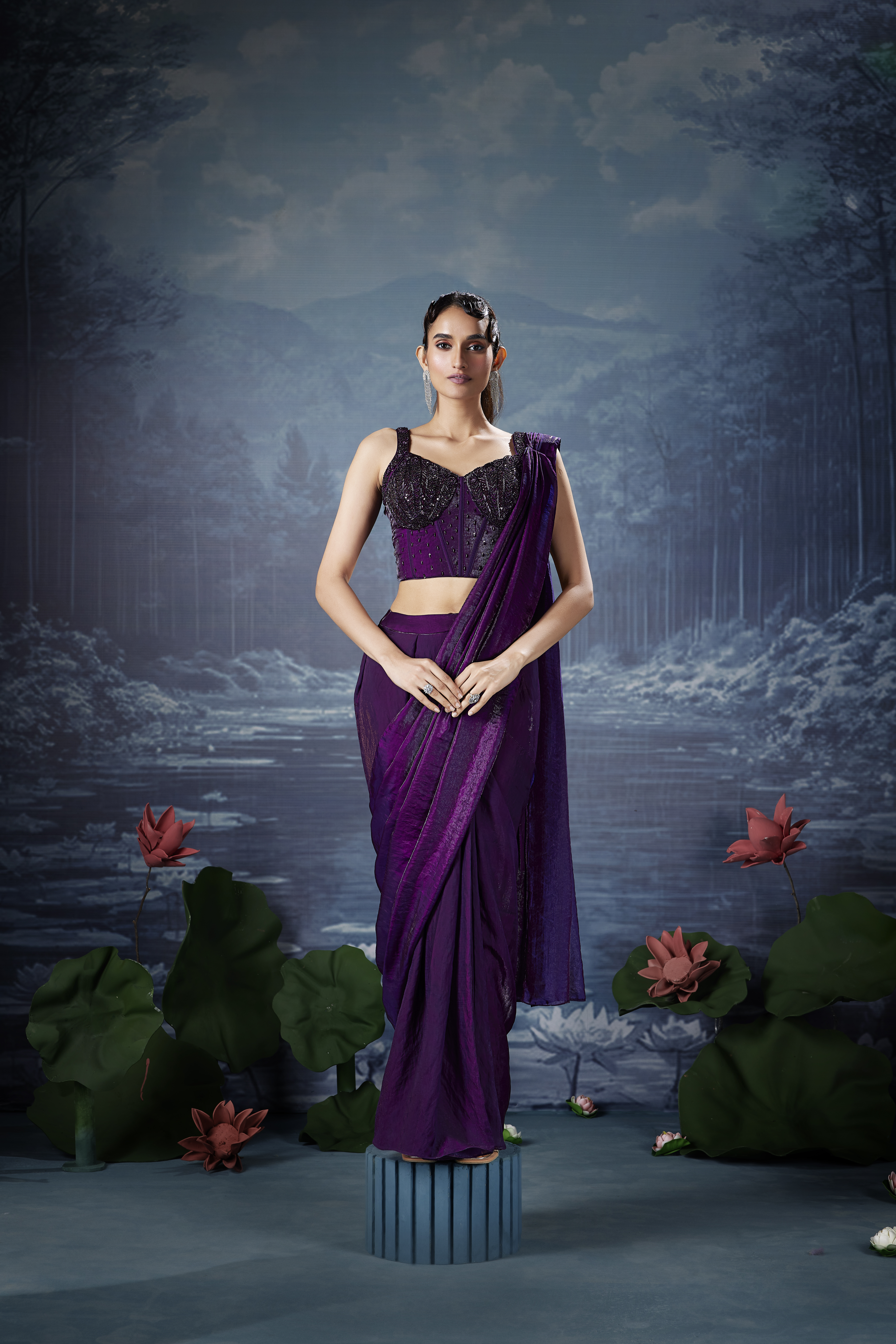 Woman wearing a royal purple designer saree with an embellished corset blouse featuring sequins and embroidery.