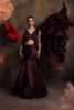 Woman wearing a plum satin fishcut drape saree gown with silver embellished sleeveless blouse and flowing pallu, posing against a floral backdrop