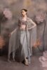 Woman wearing a silver-grey satin drape skirt with lavender mirror-work bustier and a sheer organza cape with crystal tassel embroidery, posing against a floral backdrop